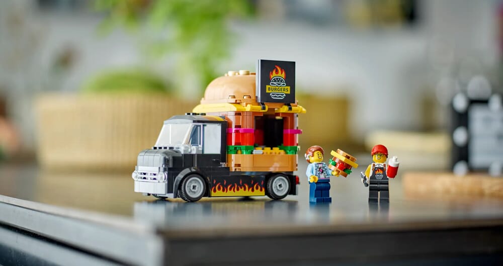 Food truck LEGO z burgerami, ozdobiony płomieniami i dwiema figurkami pracowników