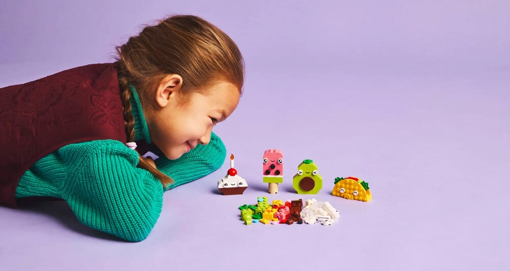 Mädchen betrachtet LEGO Food Friends Charakterset mit niedlichen Lebensmittelfiguren