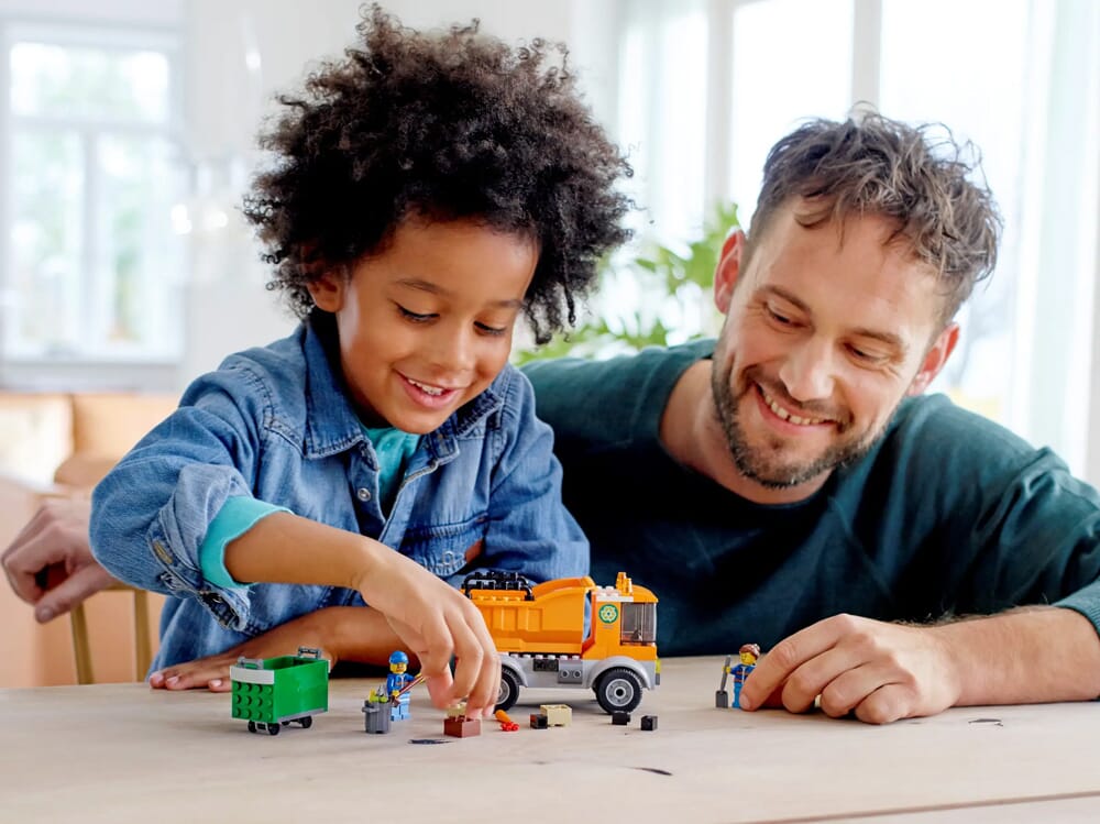 Rodzic i dziecko bawiący się zestawem śmieciarki LEGO City i minifigurkami