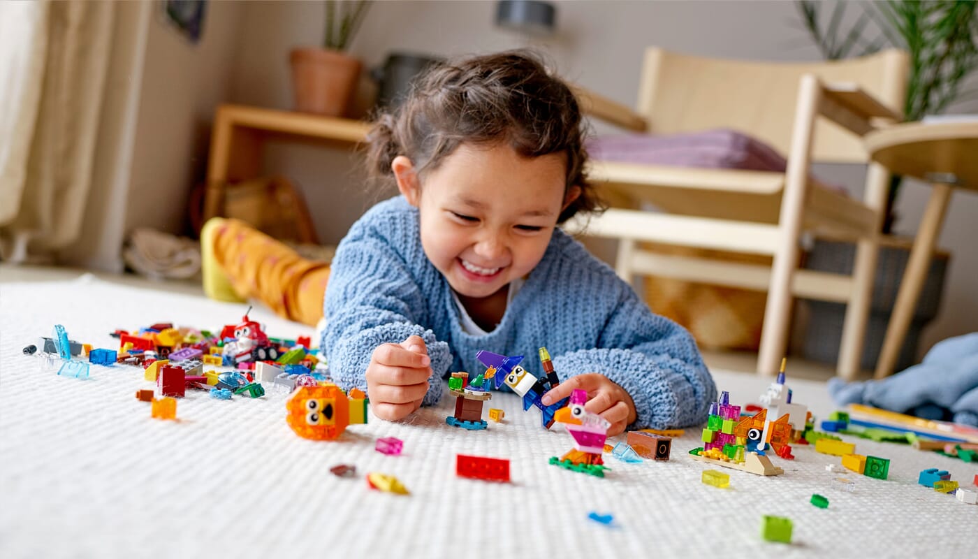 Junges Mädchen spielt mit LEGO Classic kreativen Steinen und Charakterteilen