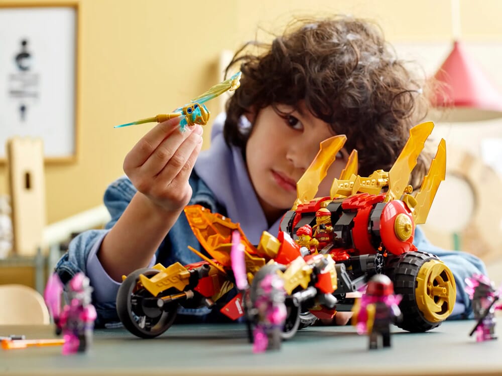 Chłopiec bawiący się zestawem LEGO NINJAGO smoczym motocyklem i minifigurkami