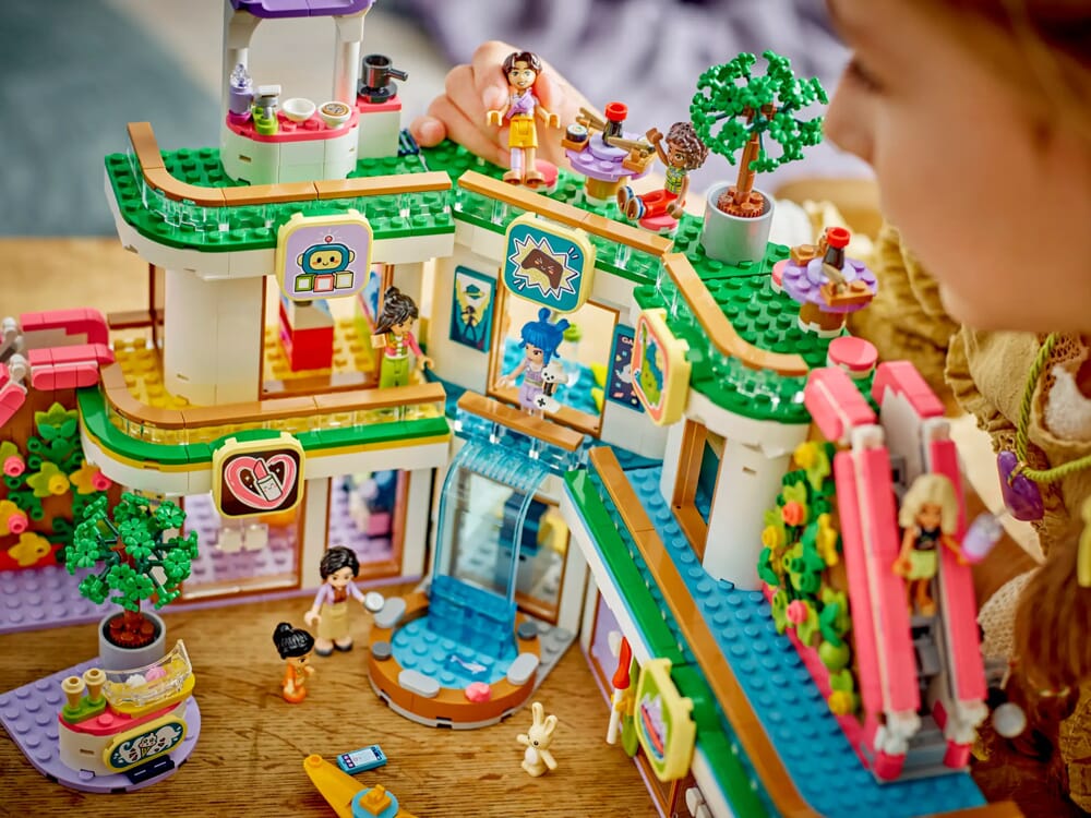 Dziewczynka bawiąca się trzypiętrowym centrum handlowym LEGO Friends z wodospadem i detalami kawiarni