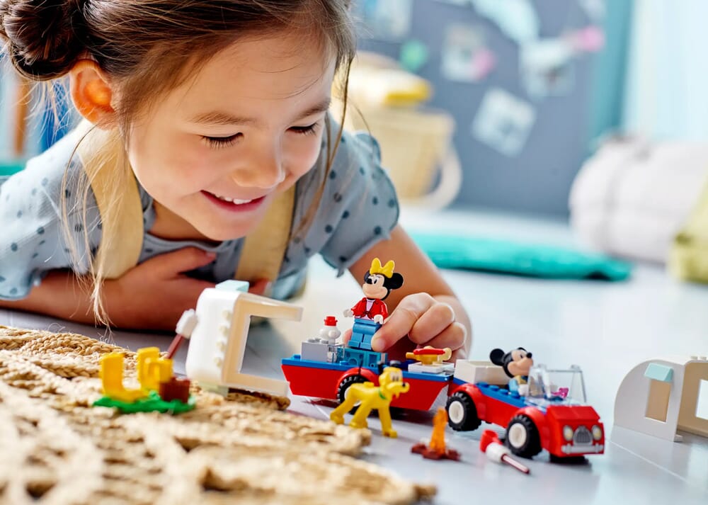Mädchen spielt mit LEGO Disney Mickey and Minnie's Camping Trailer Set