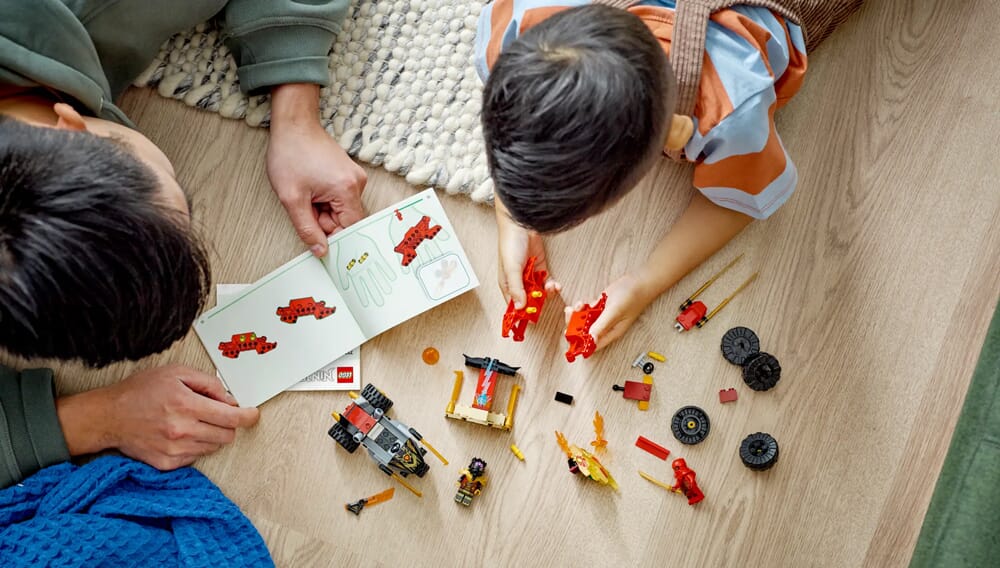 Rodzic i dziecko śledzący instrukcje budowania LEGO NINJAGO z czerwonymi figurkami ninja