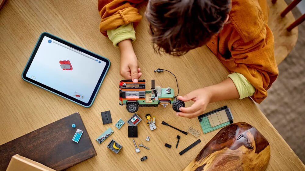Chłopiec korzystający z cyfrowej instrukcji LEGO na tablecie podczas budowania zestawu terenowego pojazdu
